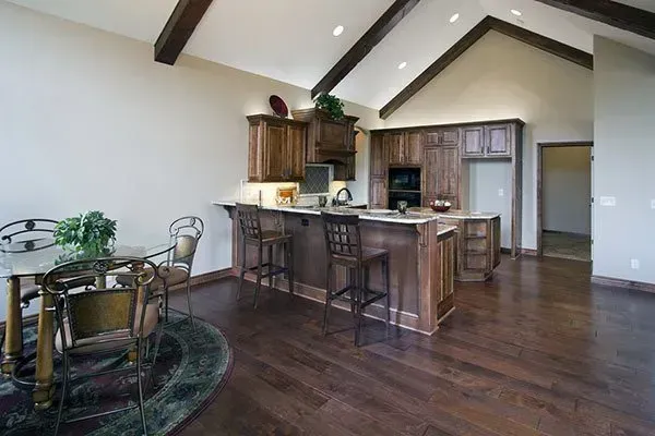 Open-concept kitchen and dining area with dark wood floors, island seating, and vaulted ceiling