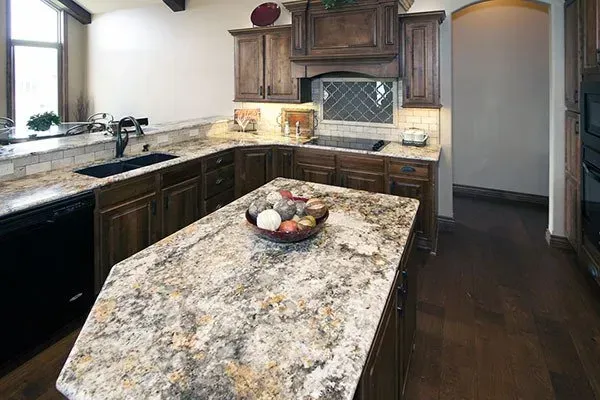 Modern kitchen with granite island, dark wood cabinets, and bowl of fruit