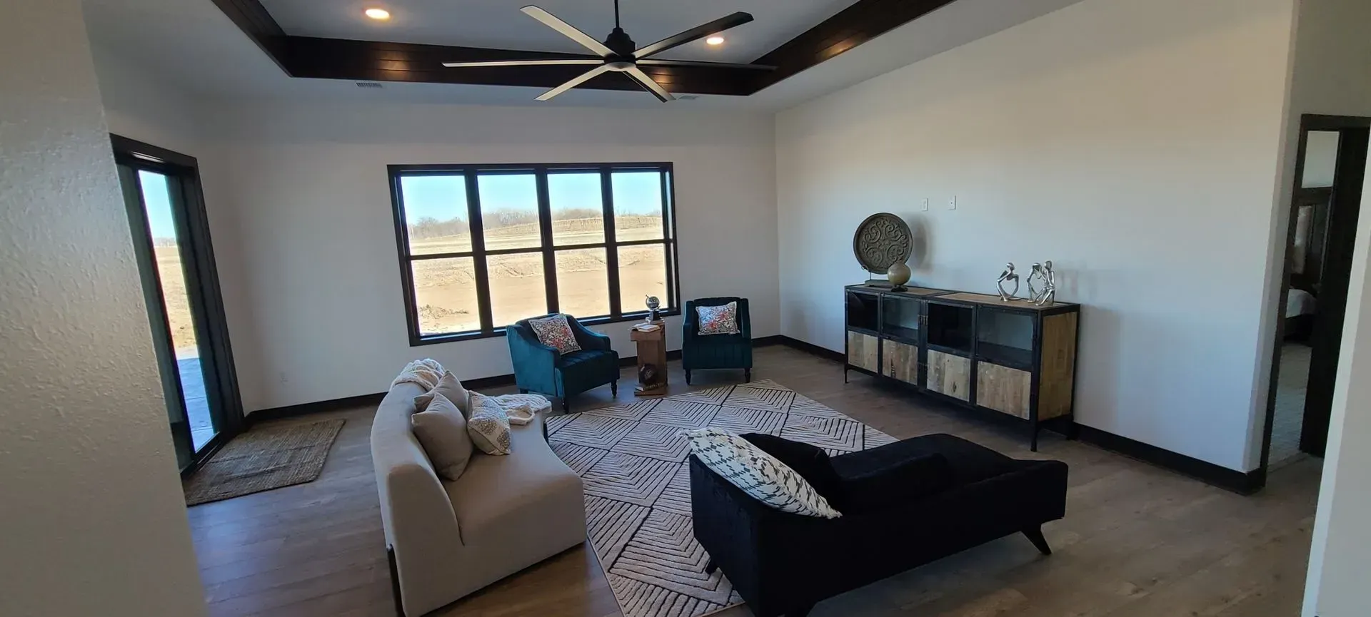 Bright living room with sectional sofa, dark coffee table, fireplace, and mountain view through large windows