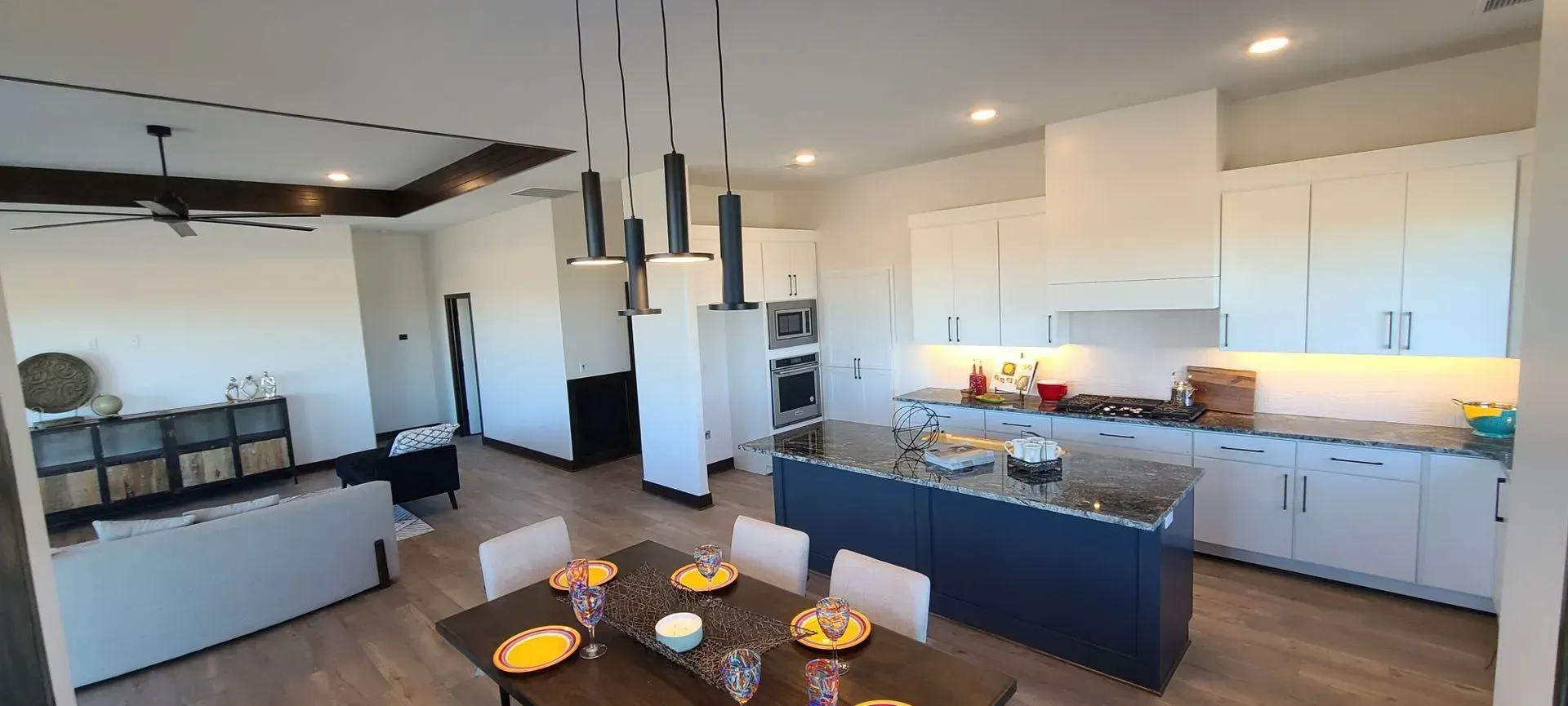 Modern open-concept kitchen and dining area with white cabinets, dark island, and pendant lights