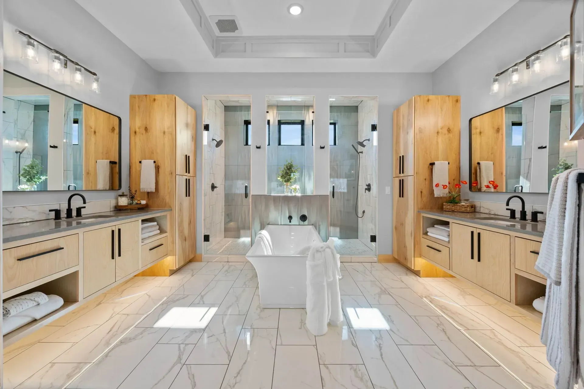 Bright modern bathroom with twin vanities, white marble floors, and a central white chair
