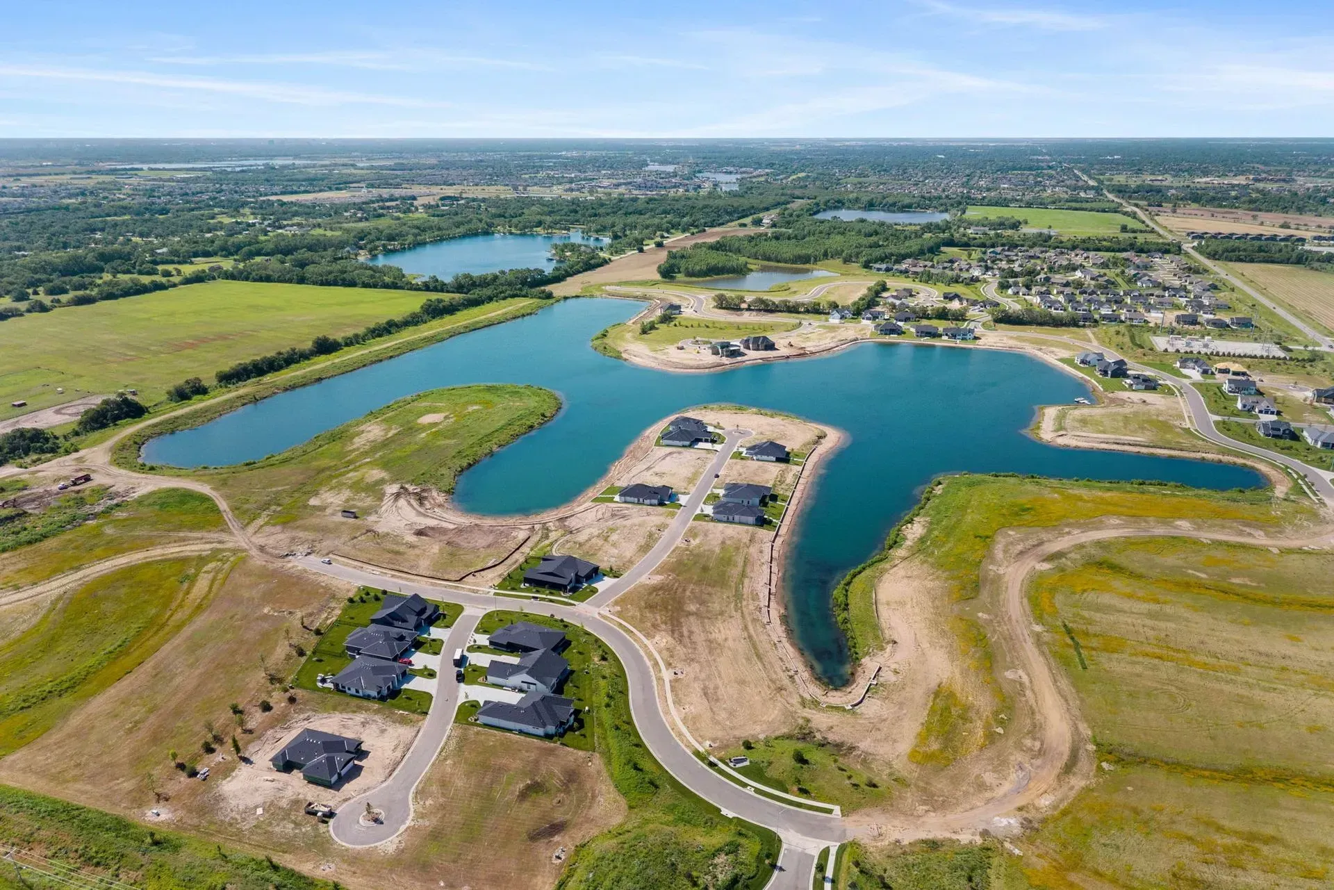 Aerial view of a new lakeside housing development with roads, homes, and blue water