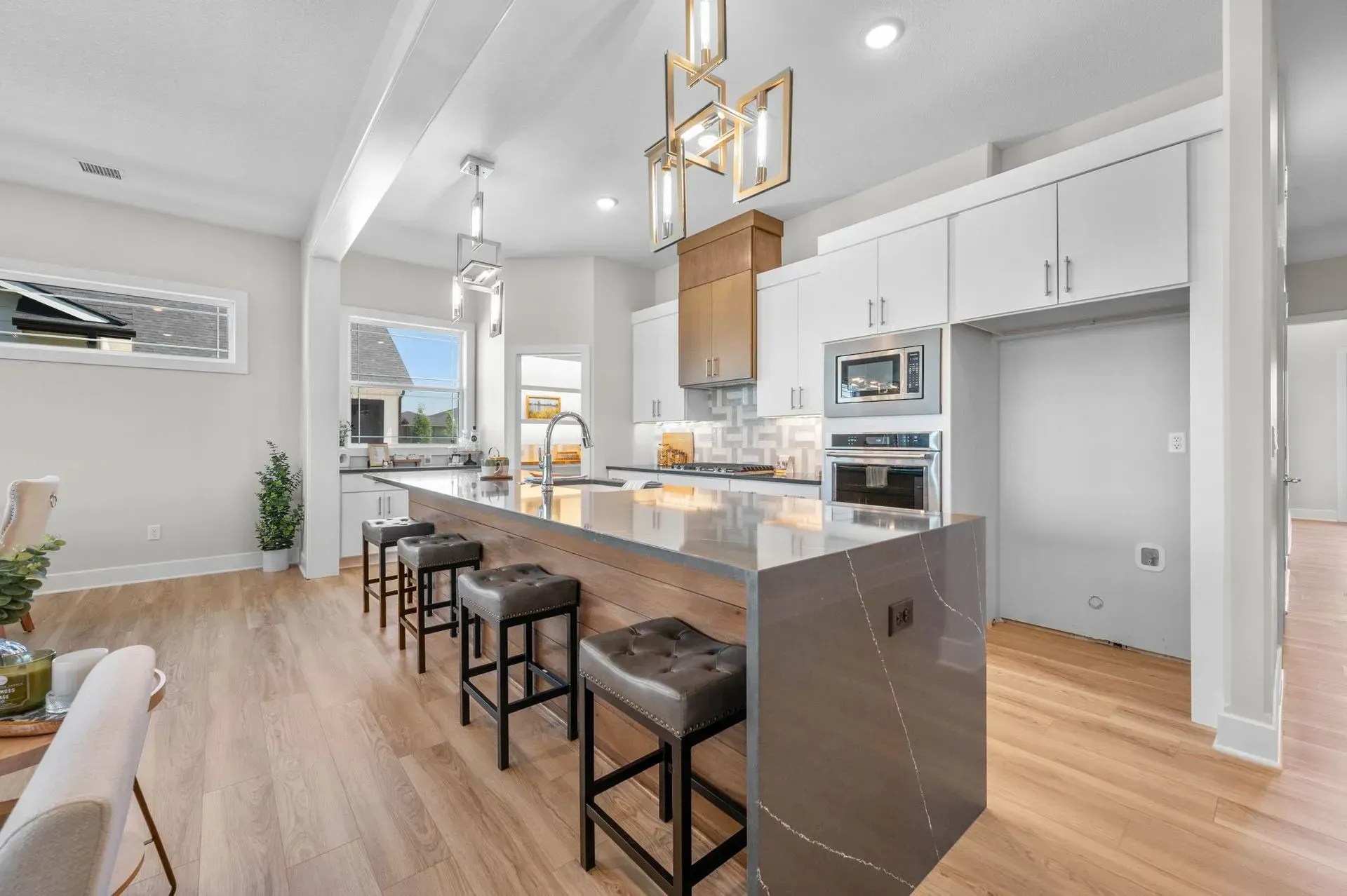 Bright modern kitchen with white cabinets, island seating, stainless appliances, and hardwood floors
