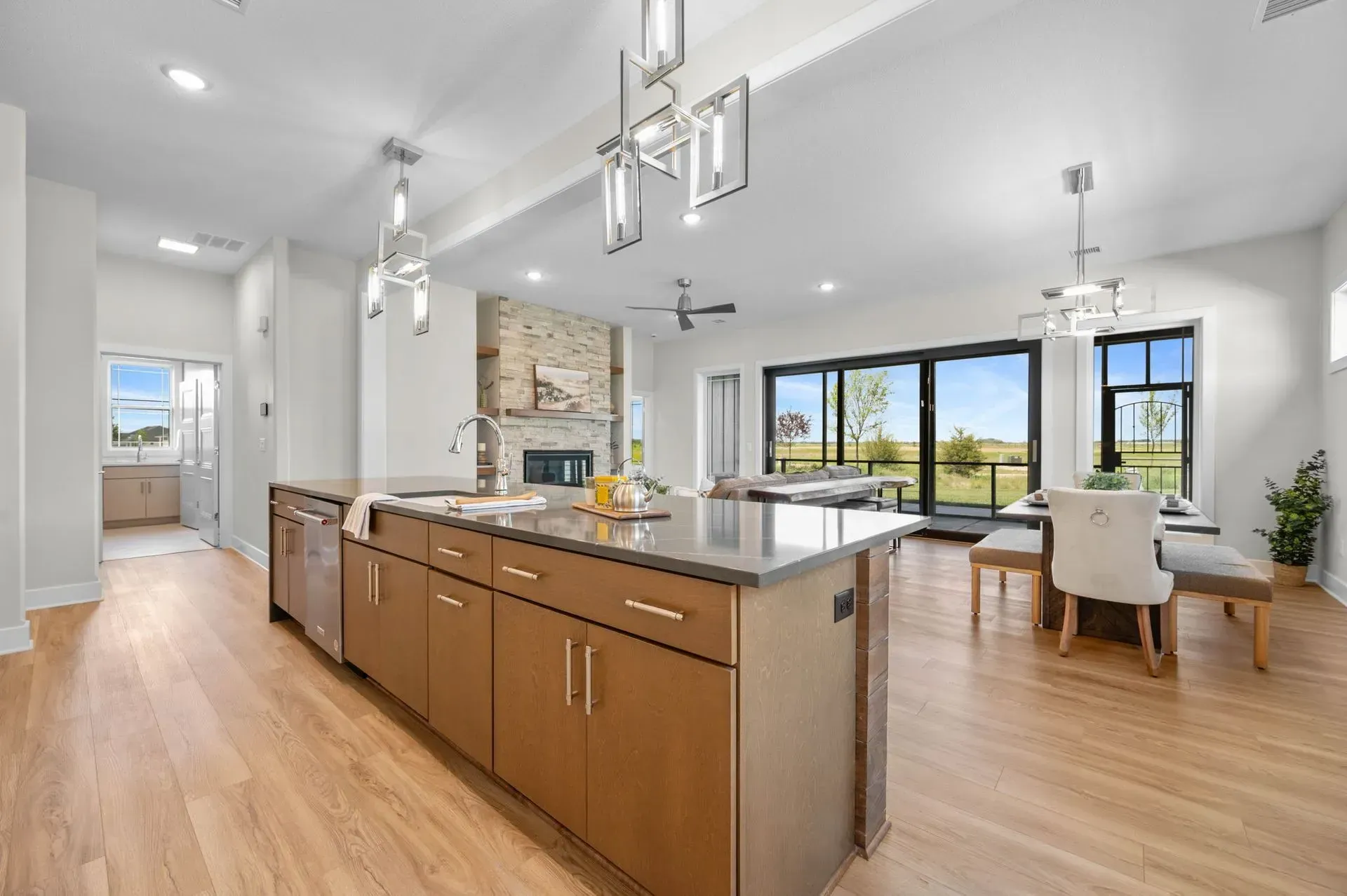 Spacious modern kitchen with wood island, white cabinets, and large windows overlooking a dining area.