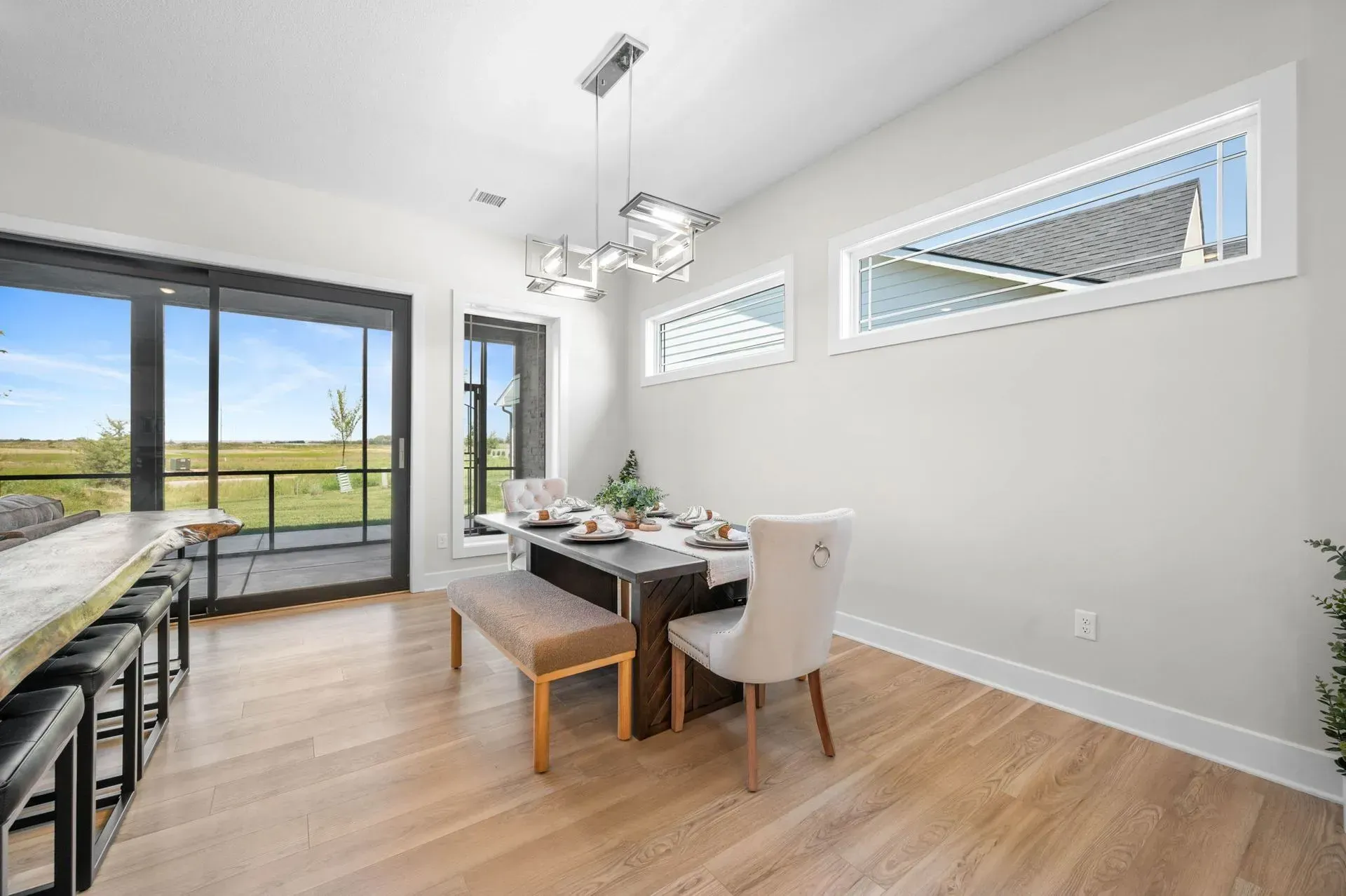 Bright dining area with wood floors, white walls, black table, and large sliding glass doors to a patio