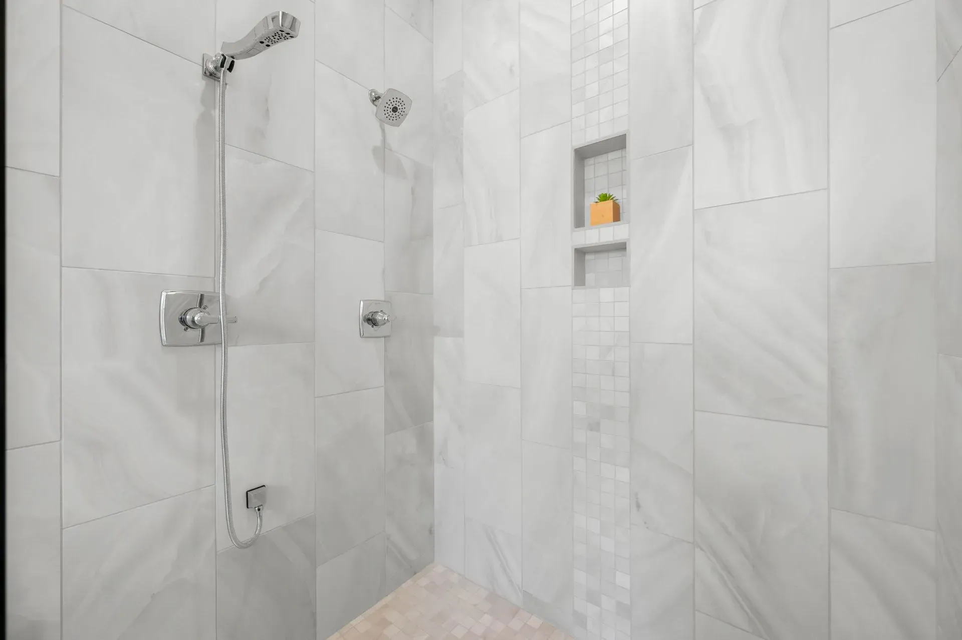 Modern tiled shower with glass doors, chrome fixtures, and built-in shelf niche