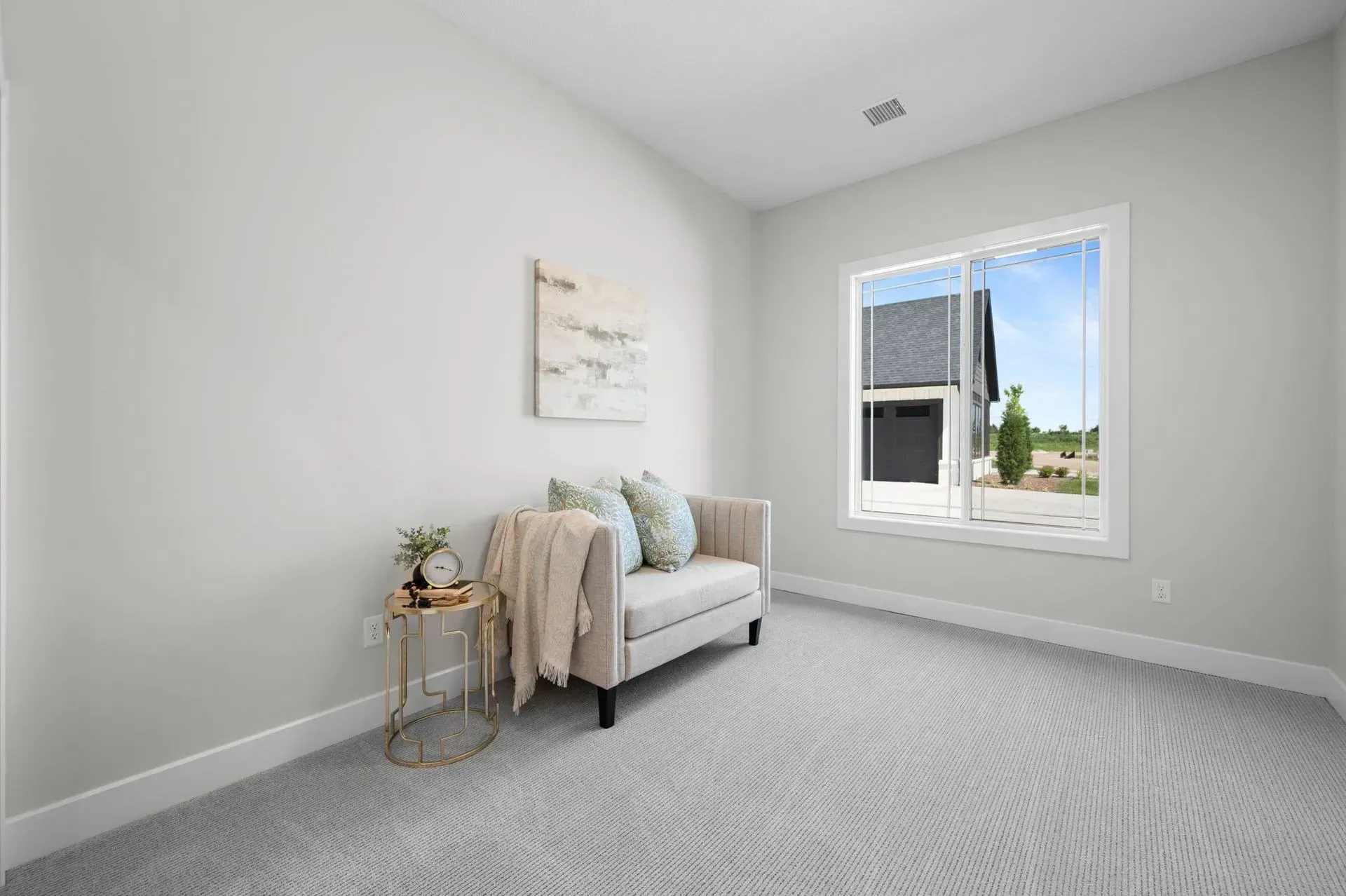 Bright empty bedroom with a small sofa, side table, and a window letting in daylight