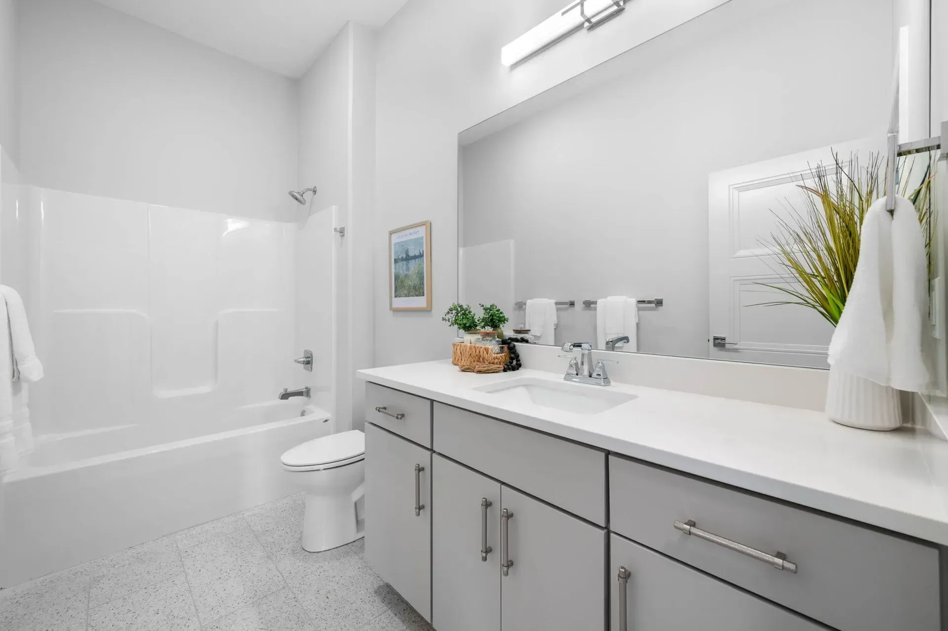 Bright white modern bathroom with a bathtub, toilet, and vanity with mirror