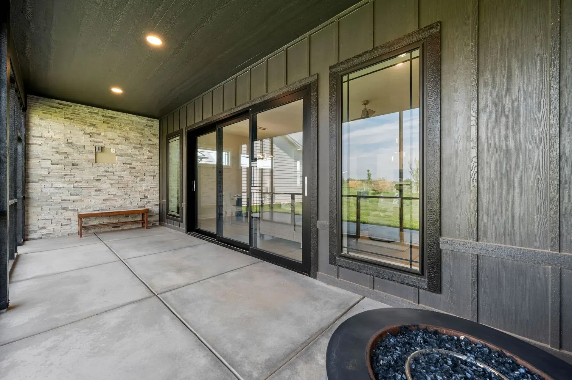 Covered patio with sliding glass doors, stone accent wall, and concrete floor.