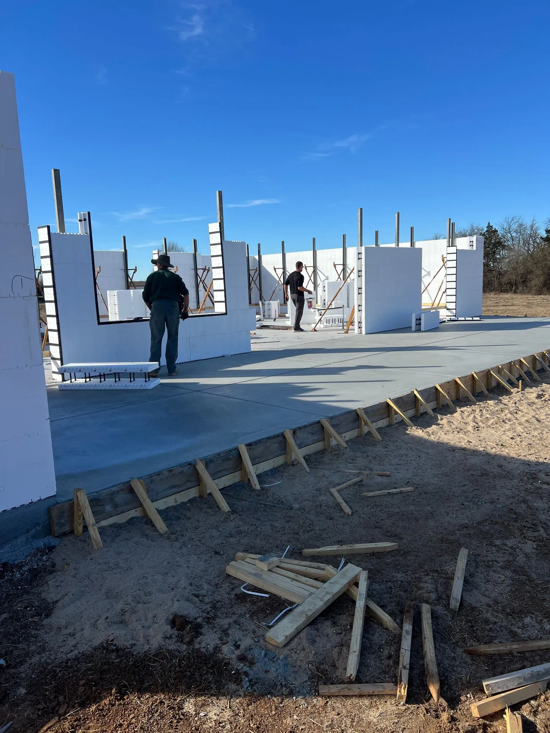 Partially built concrete structure at a construction site under a clear blue sky
