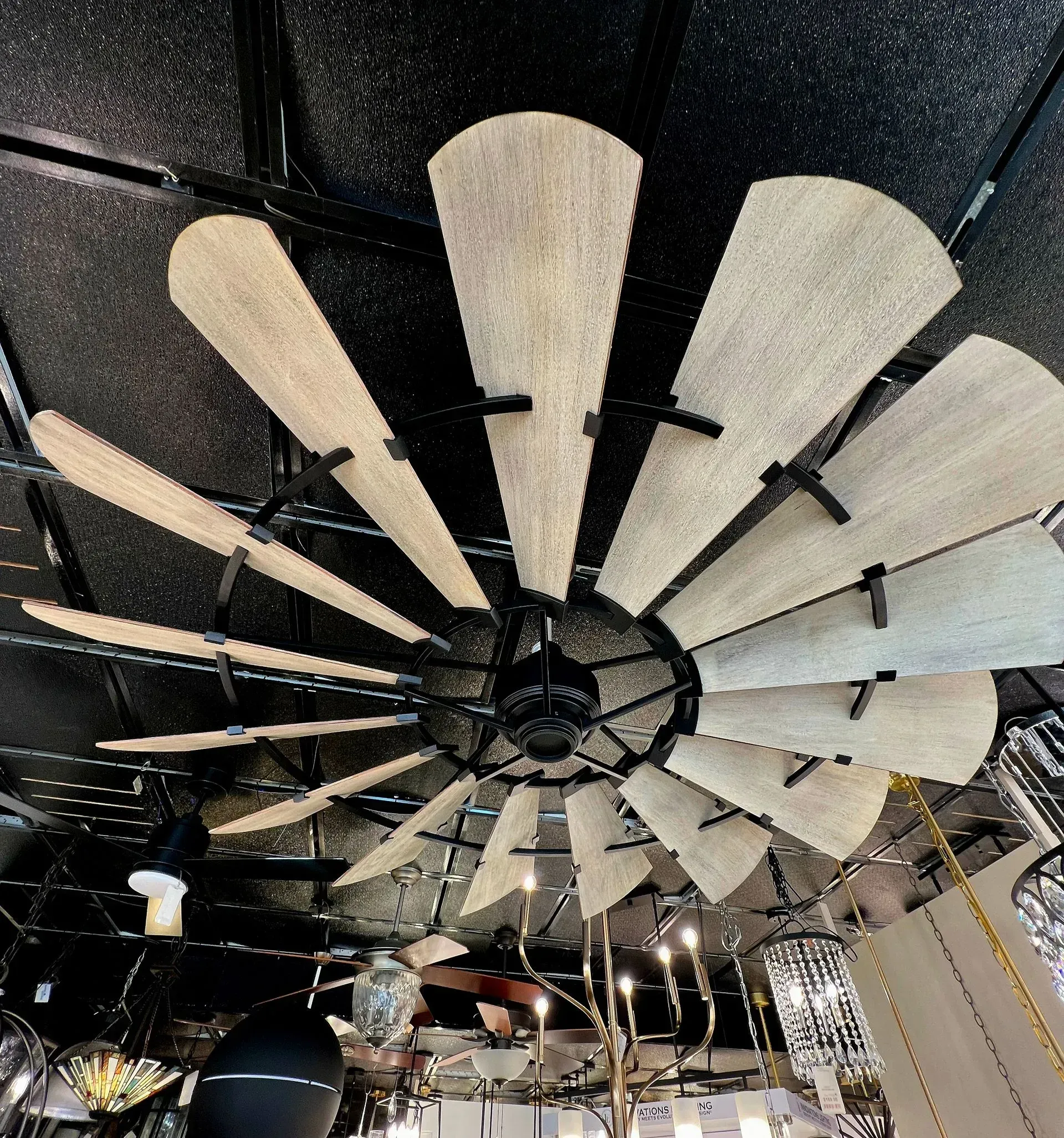 Large ceiling fan with beige blades under a dark industrial ceiling