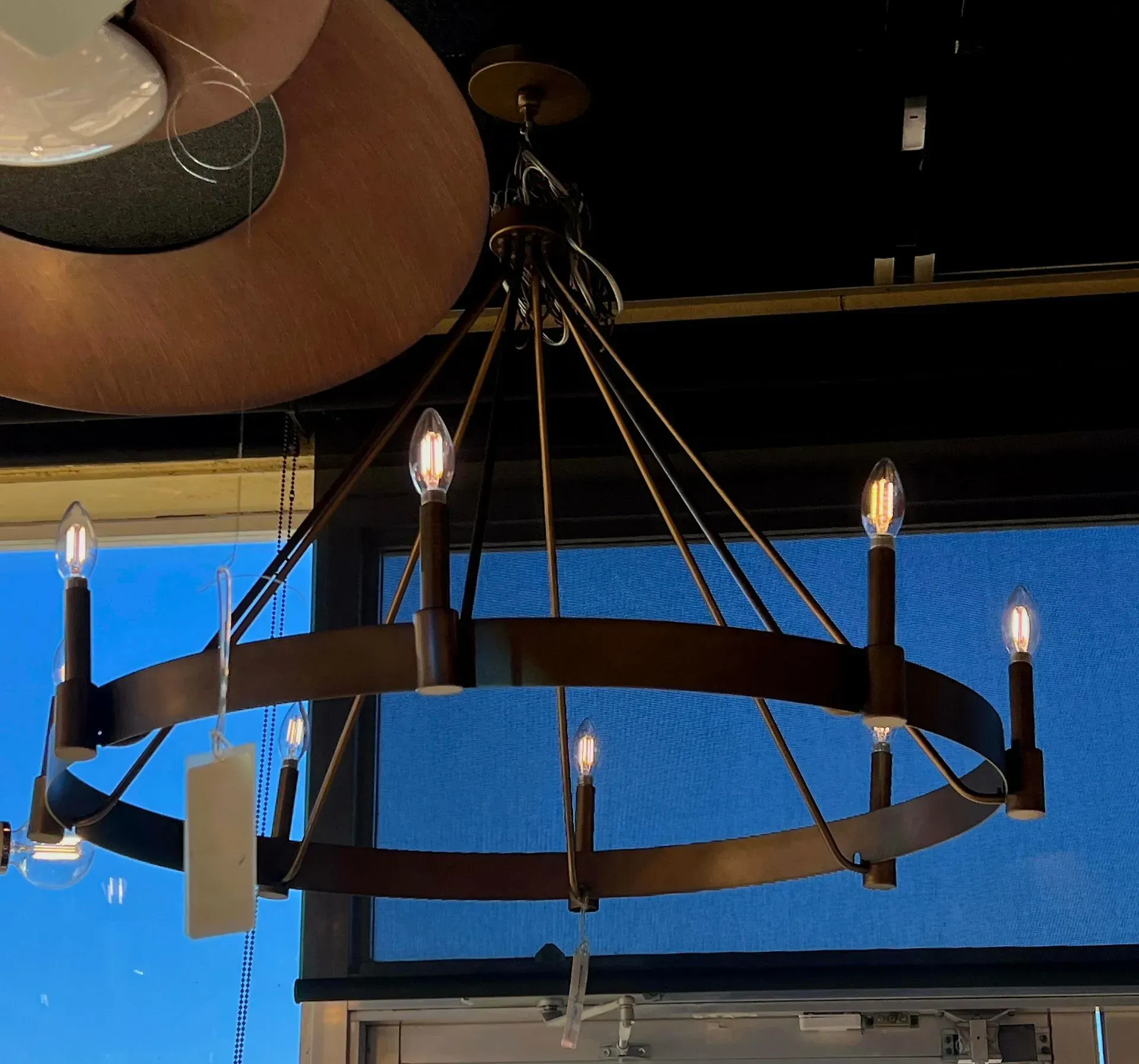Hanging black metal chandelier with candle-style bulbs against a blue wall