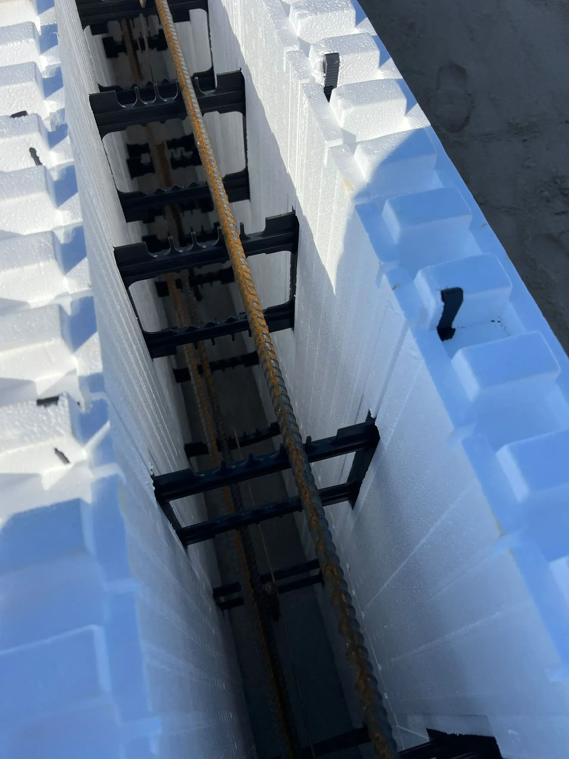 Top-down view of a model train track laid between white foam blocks with blue edges.