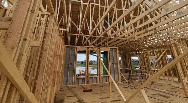 Wood-framed house interior under construction with exposed rafters and window openings