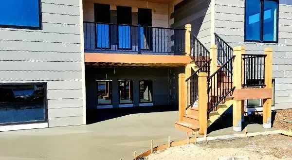 Apartment building exterior with balcony and wooden stairs in bright sunlight