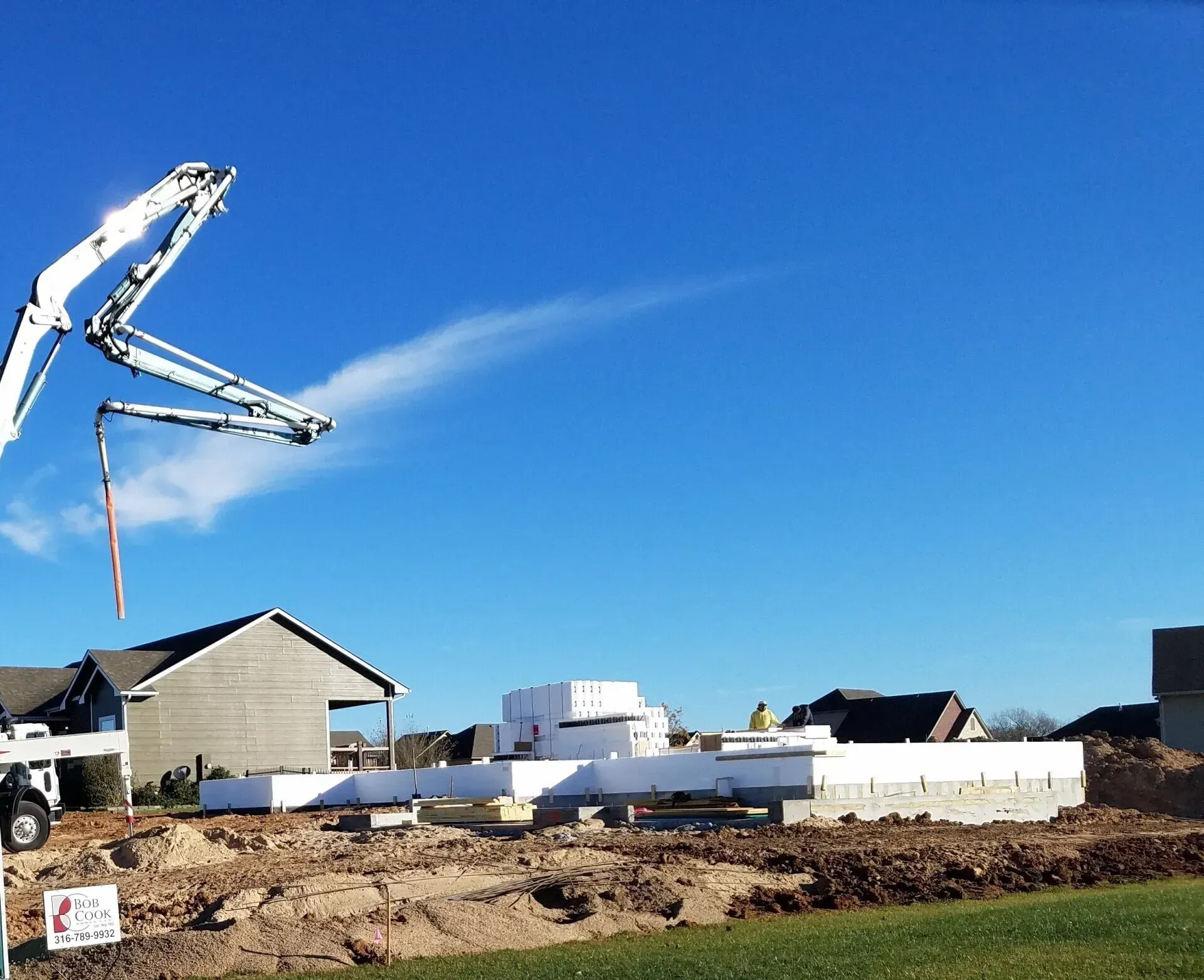 Concrete pump truck pouring at a residential construction site under a clear blue sky