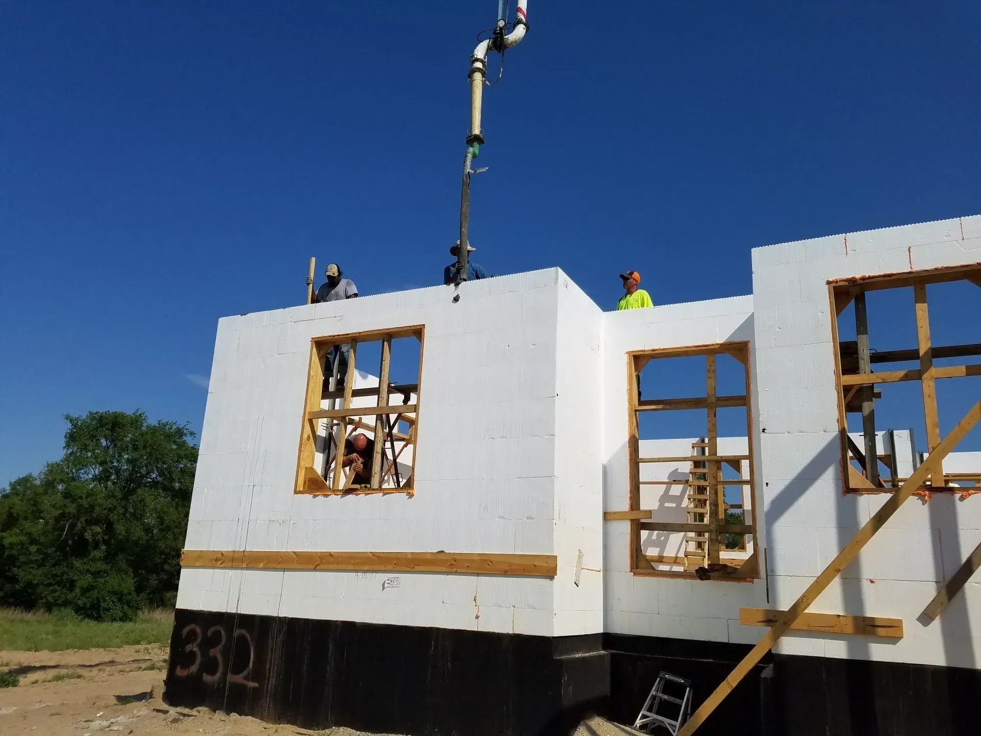 Workers installing white house wall panels at a construction site under a blue sky