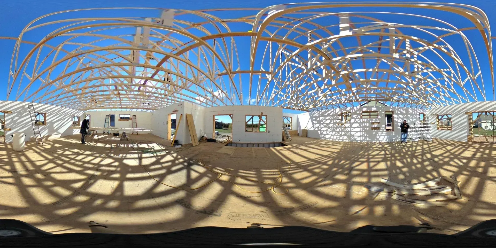 Empty white gallery with tan floor and an intricate blue-and-brown looping ceiling sculpture