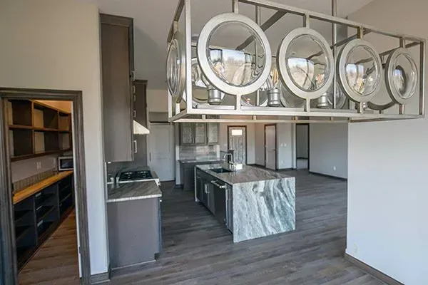 Modern open kitchen with marble island, pendant lights, gray cabinets, and dark wood floors