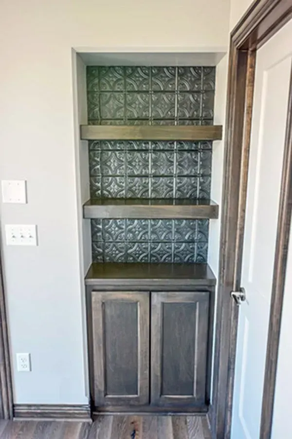 Built-in wall cabinet with dark wood doors and glass shelves in a hallway niche