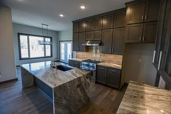 Modern kitchen with dark wood cabinets, granite island, and large windows letting in natural light