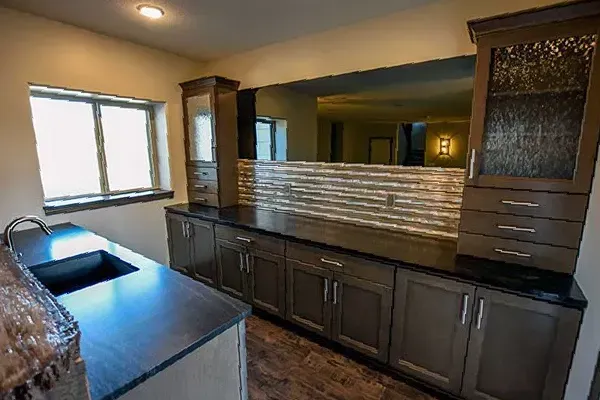Modern kitchen with dark cabinets, large window, and island with sink and backsplash divider