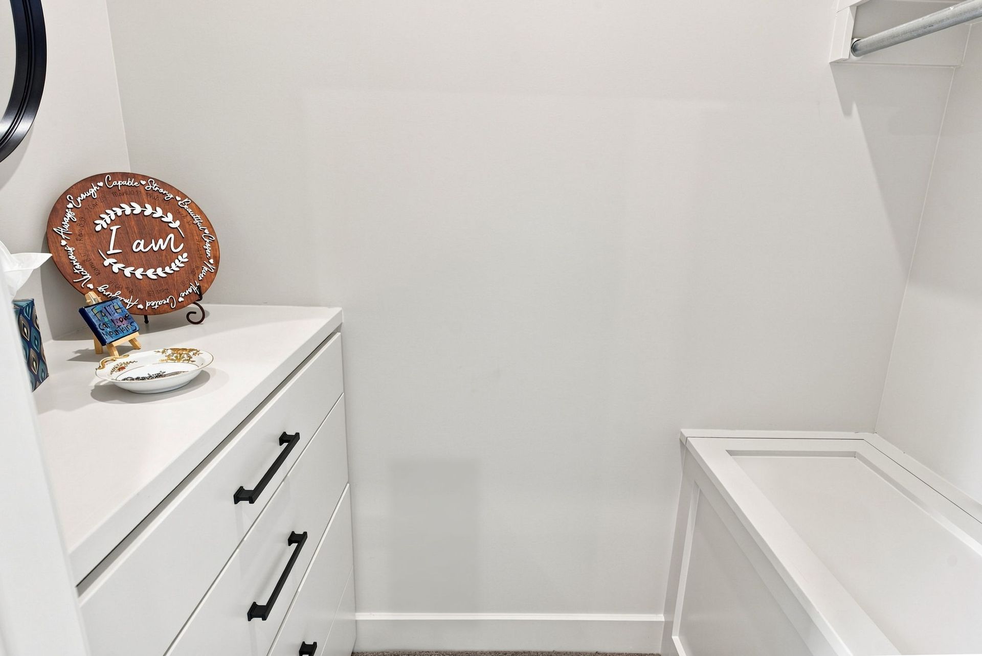 White laundry room with dresser, basket, and ironing board along the walls.