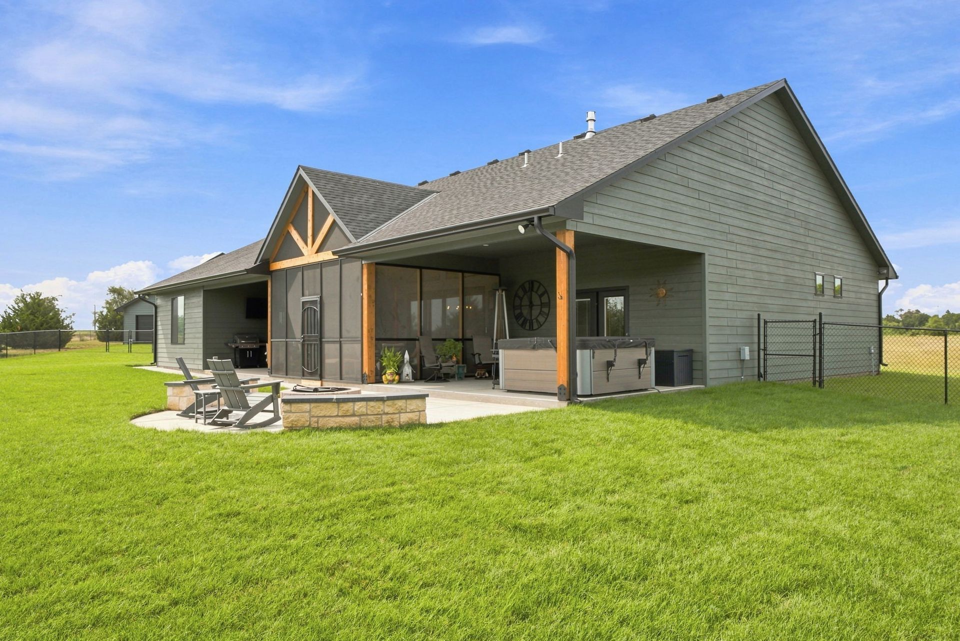 Modern gray house with a covered patio and green lawn under a cloudy sky