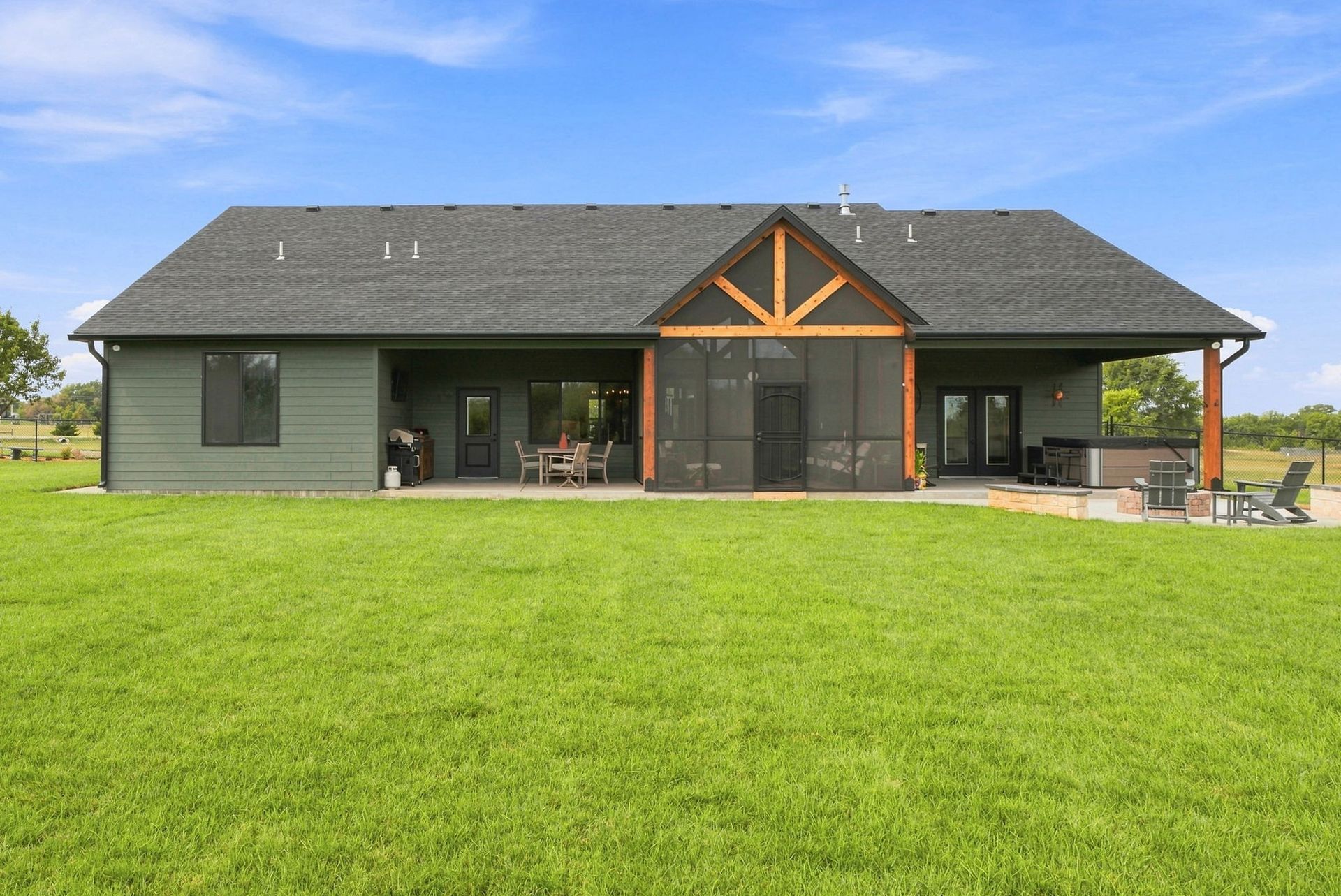 Modern dark-gray house with a large green lawn and covered front porch