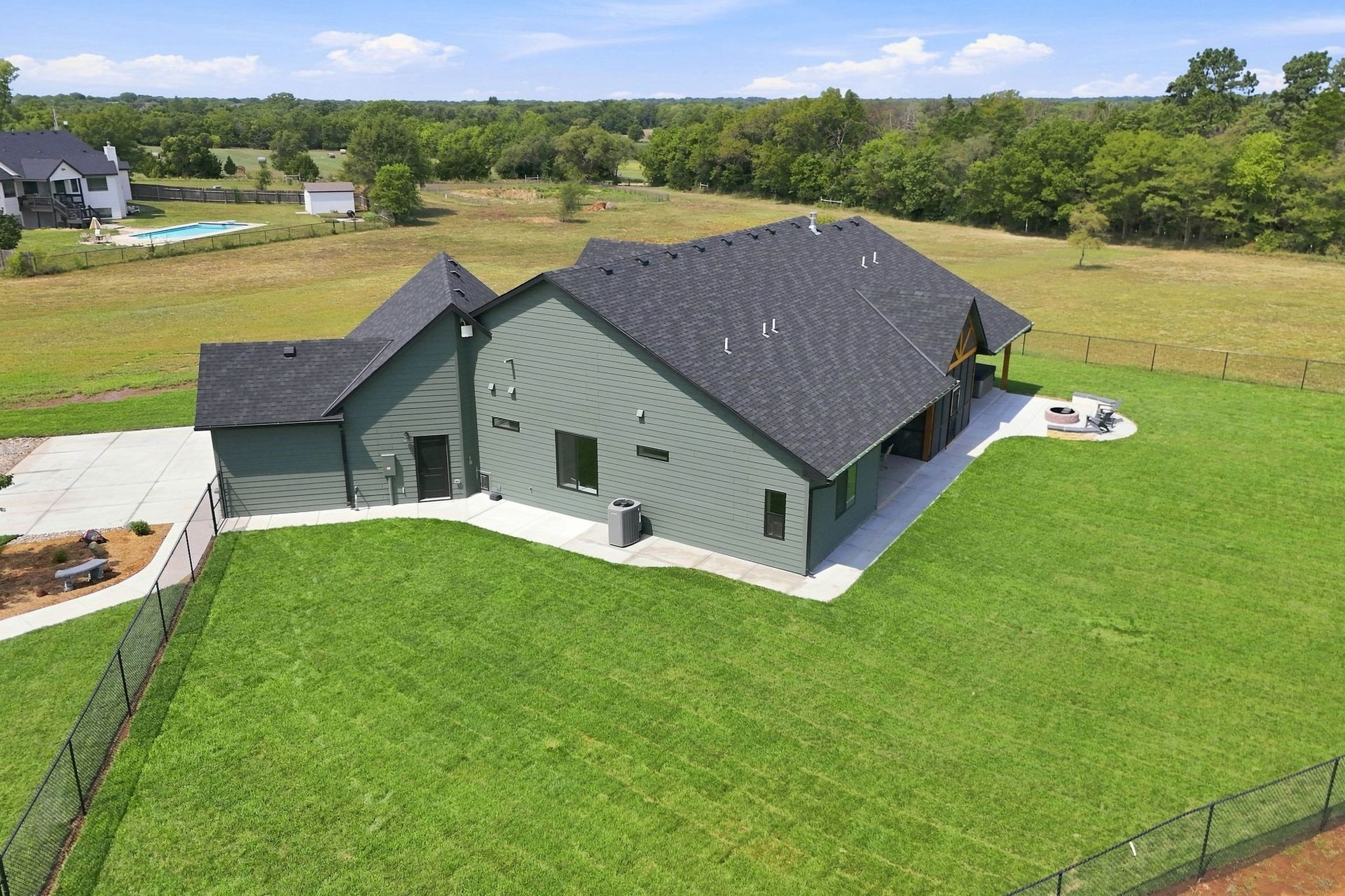 Aerial view of a gray-roofed house with a large green lawn in a rural neighborhood