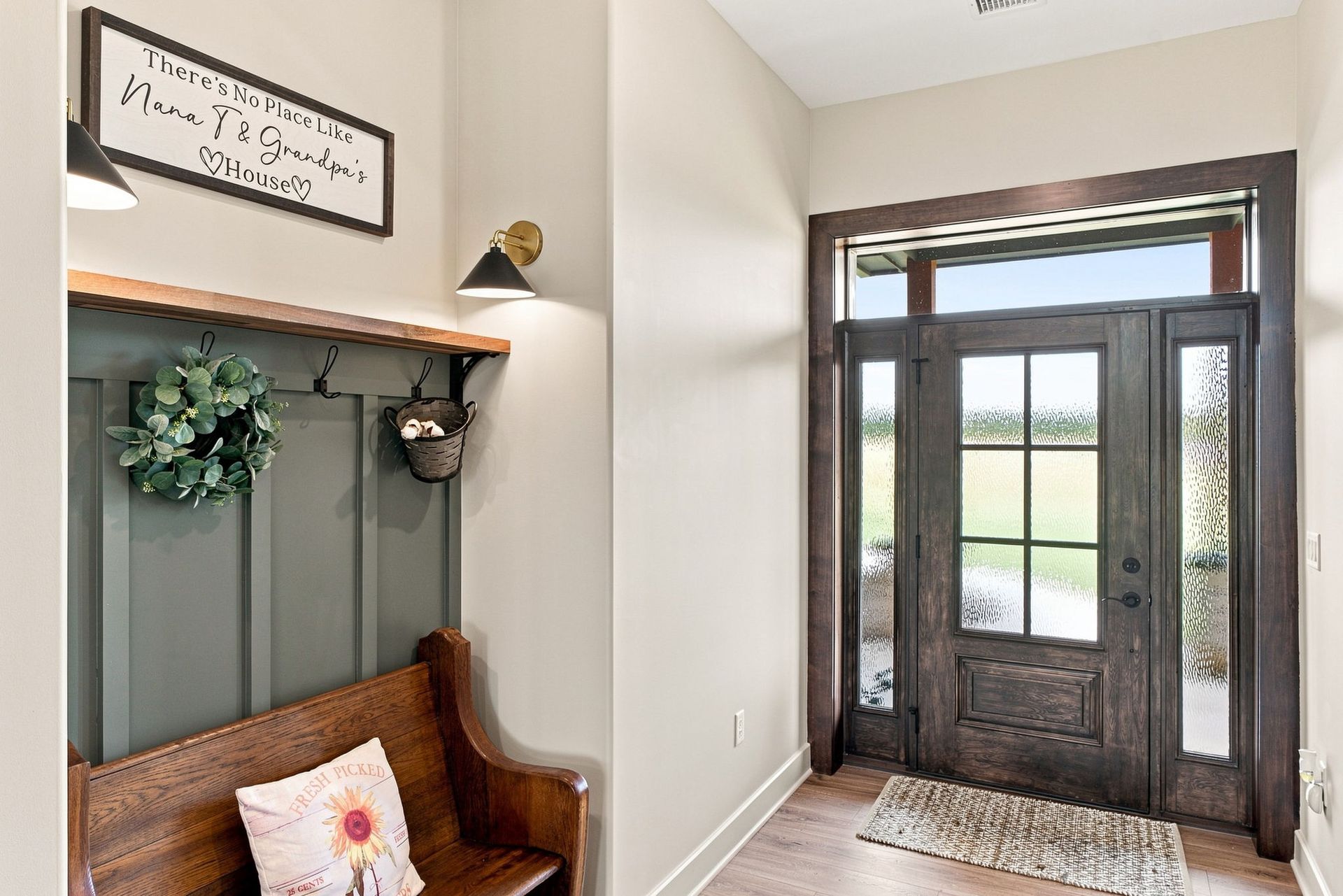 Entryway with rustic bench, wall hooks, and a dark wood front door with glass panels.