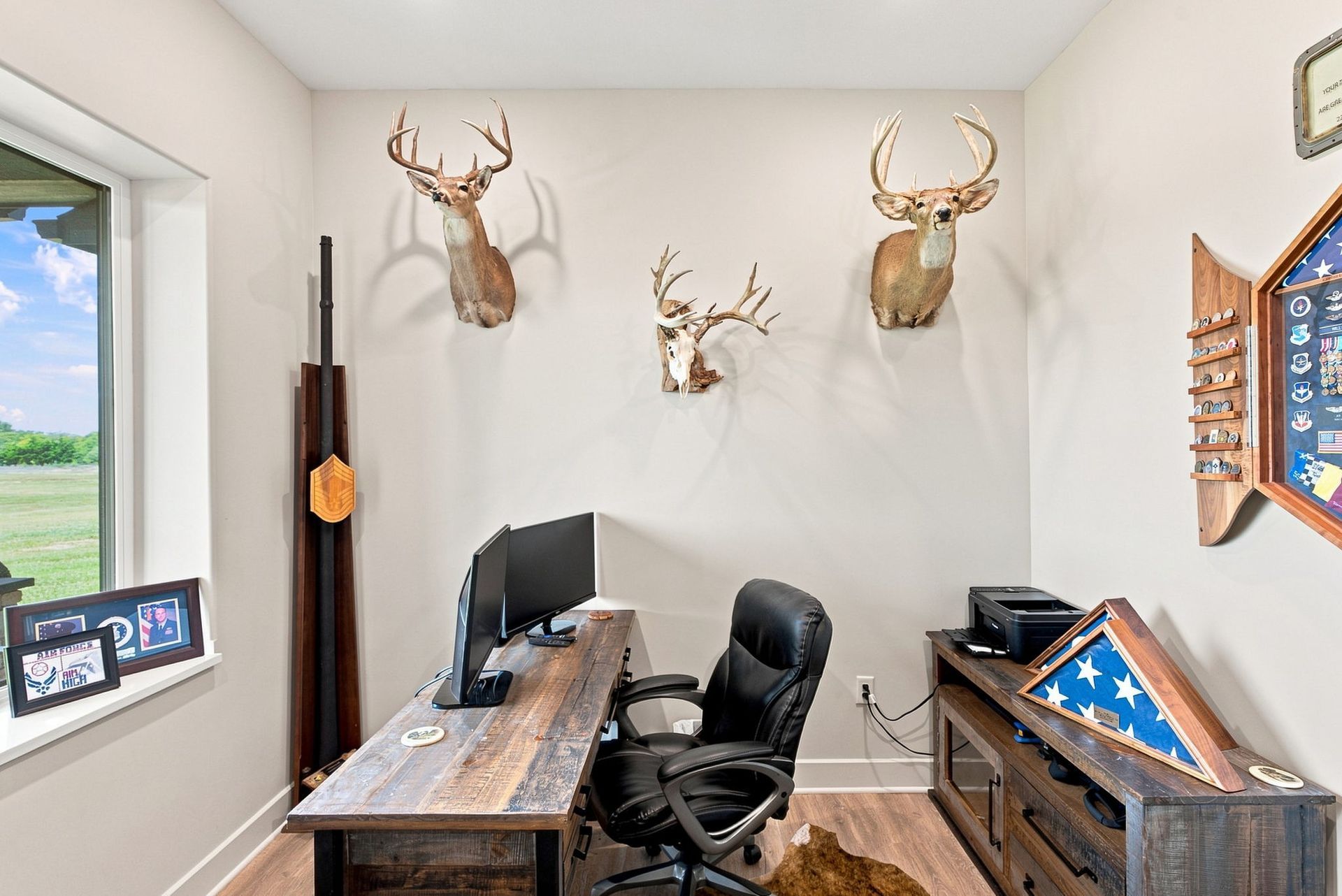 Small office with desk, chair, computer, mounted deer heads, and patriotic decor