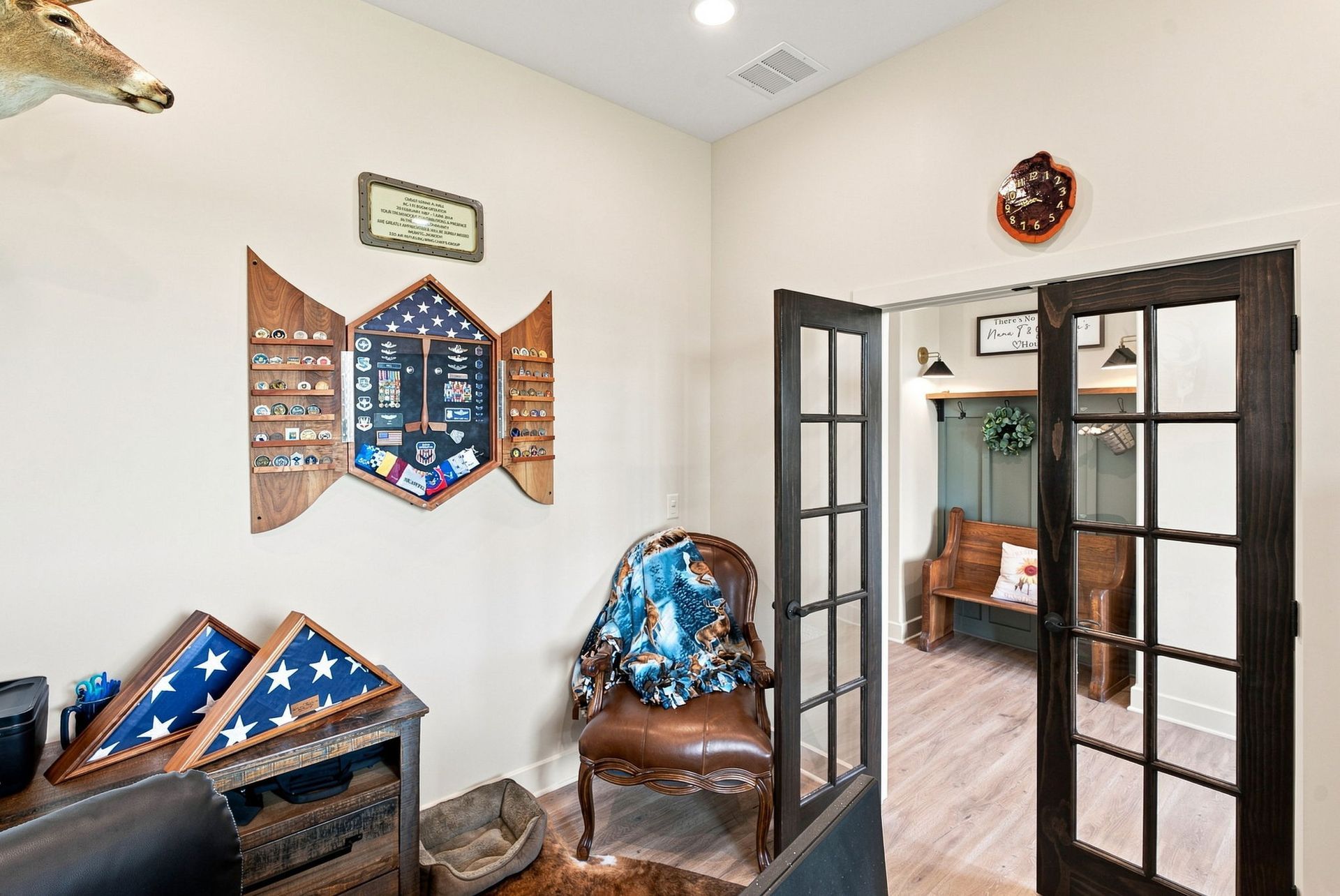 Cozy room with framed art, a chair, and glass French doors leading to a sunroom.
