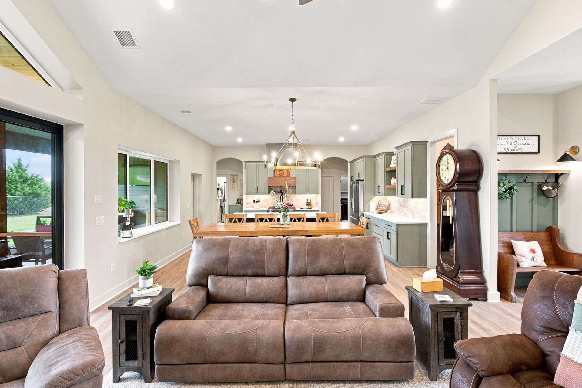 Bright living room with beige sofa, recliners, and open view to a modern kitchen