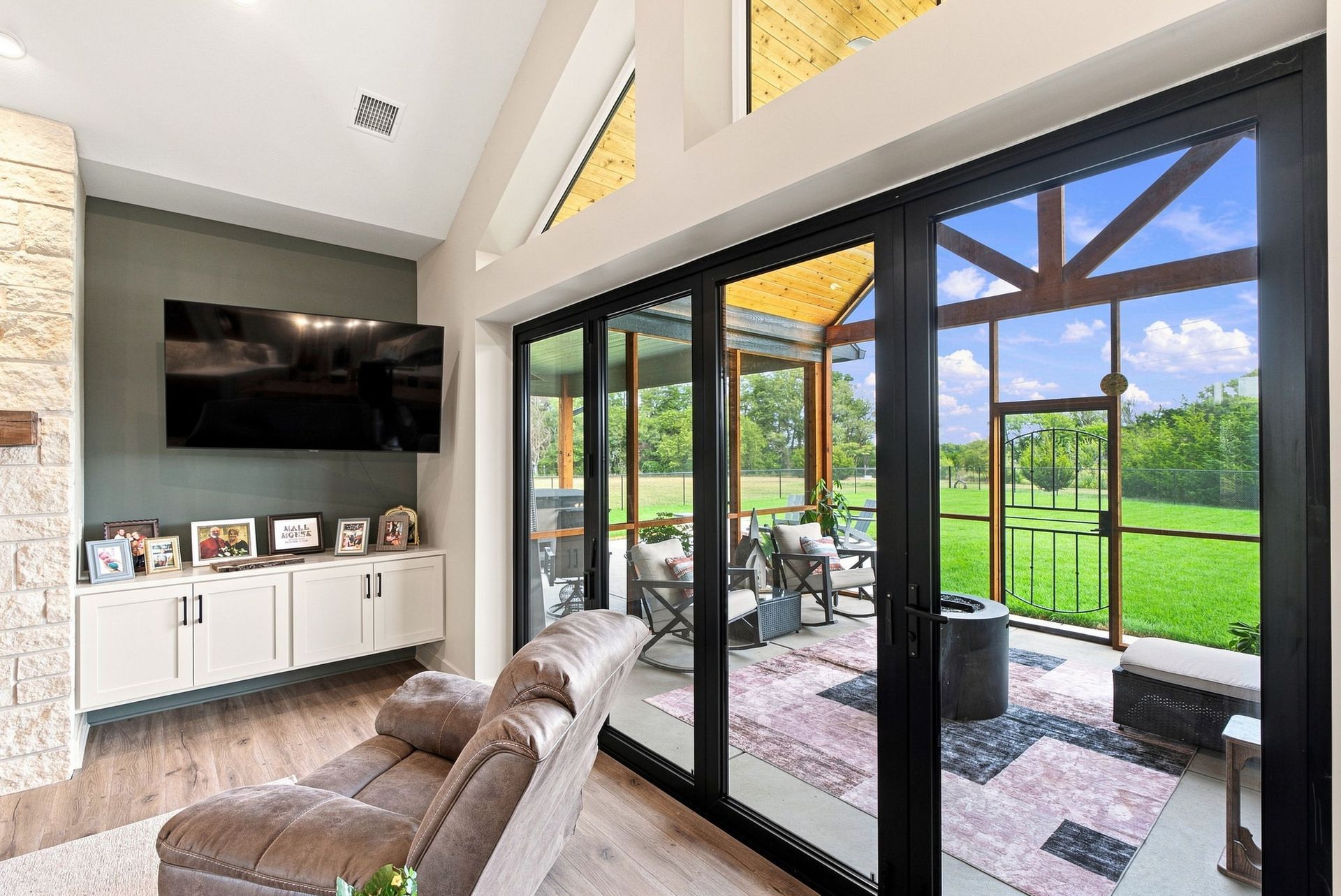 Bright living room with TV, sectional chair, and large glass doors opening to a covered patio and green yard