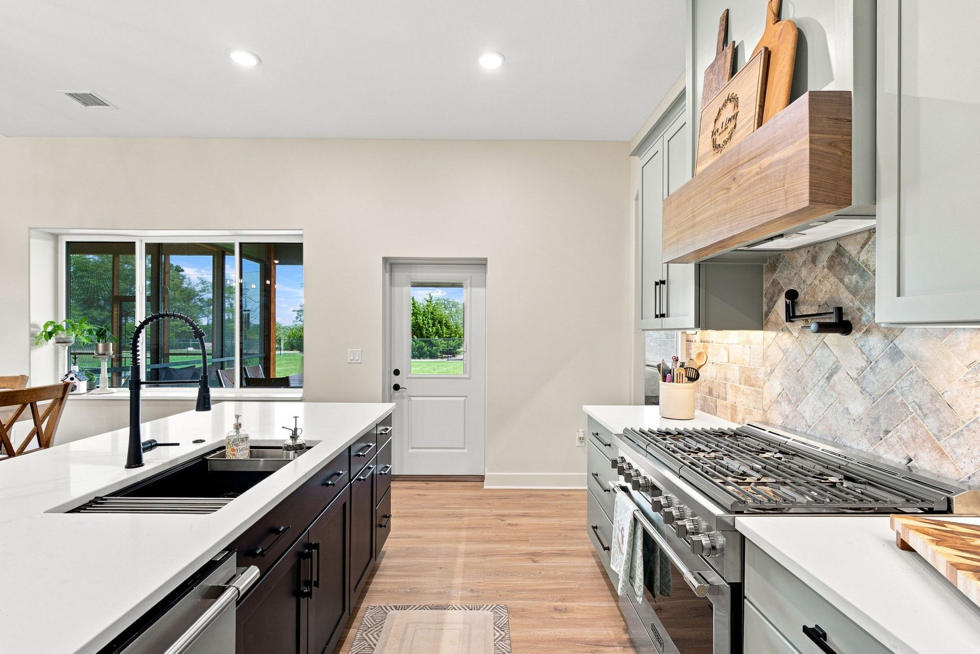 Modern kitchen with white cabinets, black island sink, marble backsplash, and wood floors