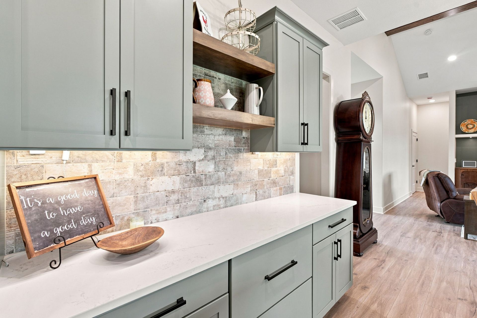 Modern kitchen hallway with sage cabinets, white countertop, and chalkboard sign