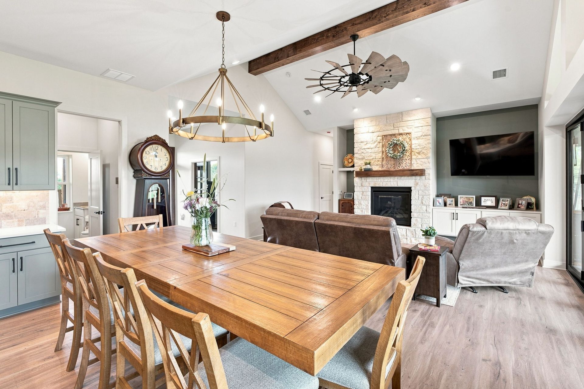 Open-concept kitchen and living room with wooden dining table, fireplace, and wall-mounted TV