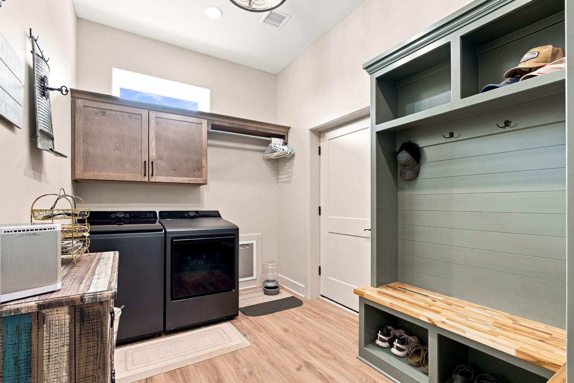Laundry room with washer and dryer, wall cabinets, and built-in storage bench on wood flooring