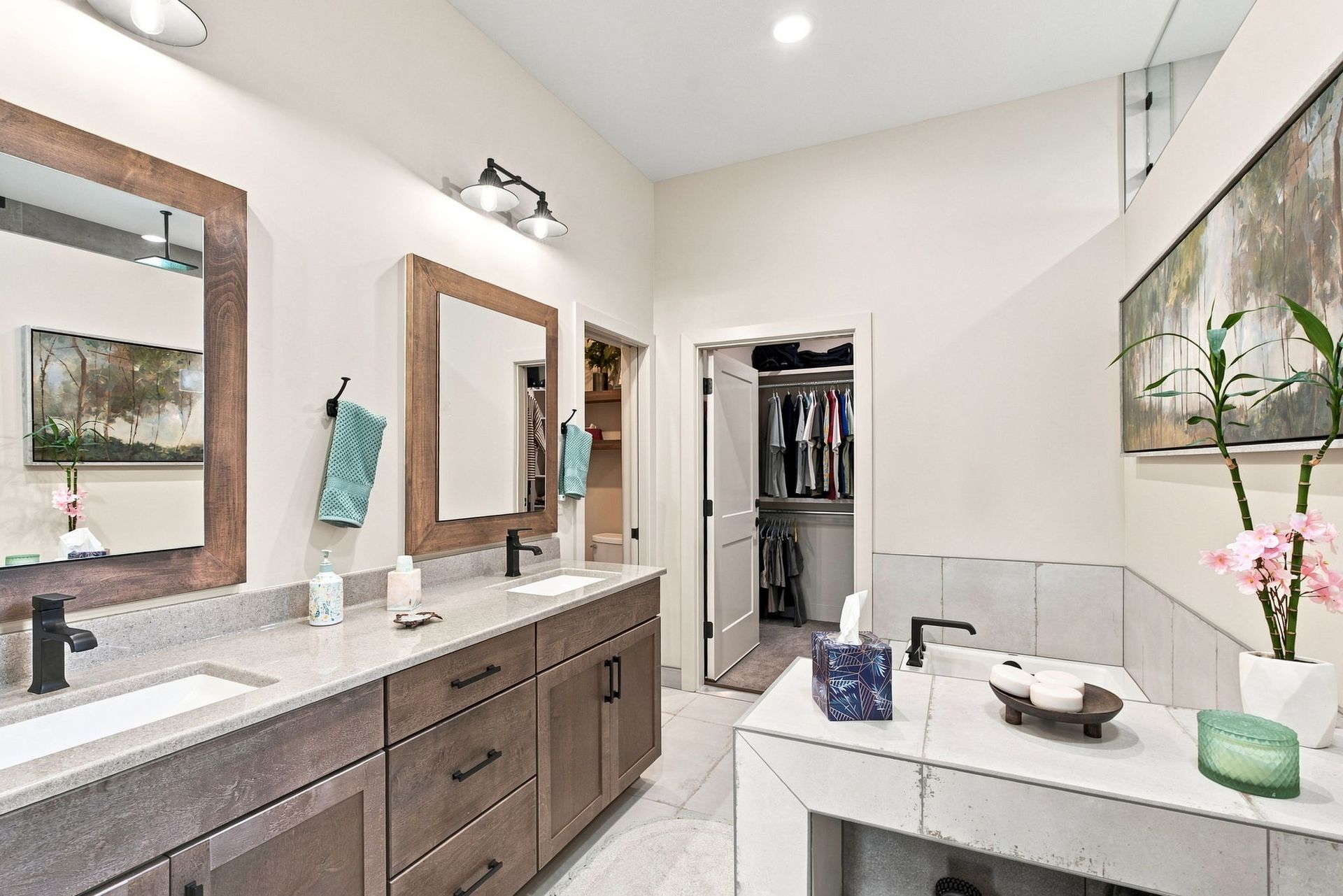 Bright modern bathroom with double vanity, large mirrors, and open closet area.