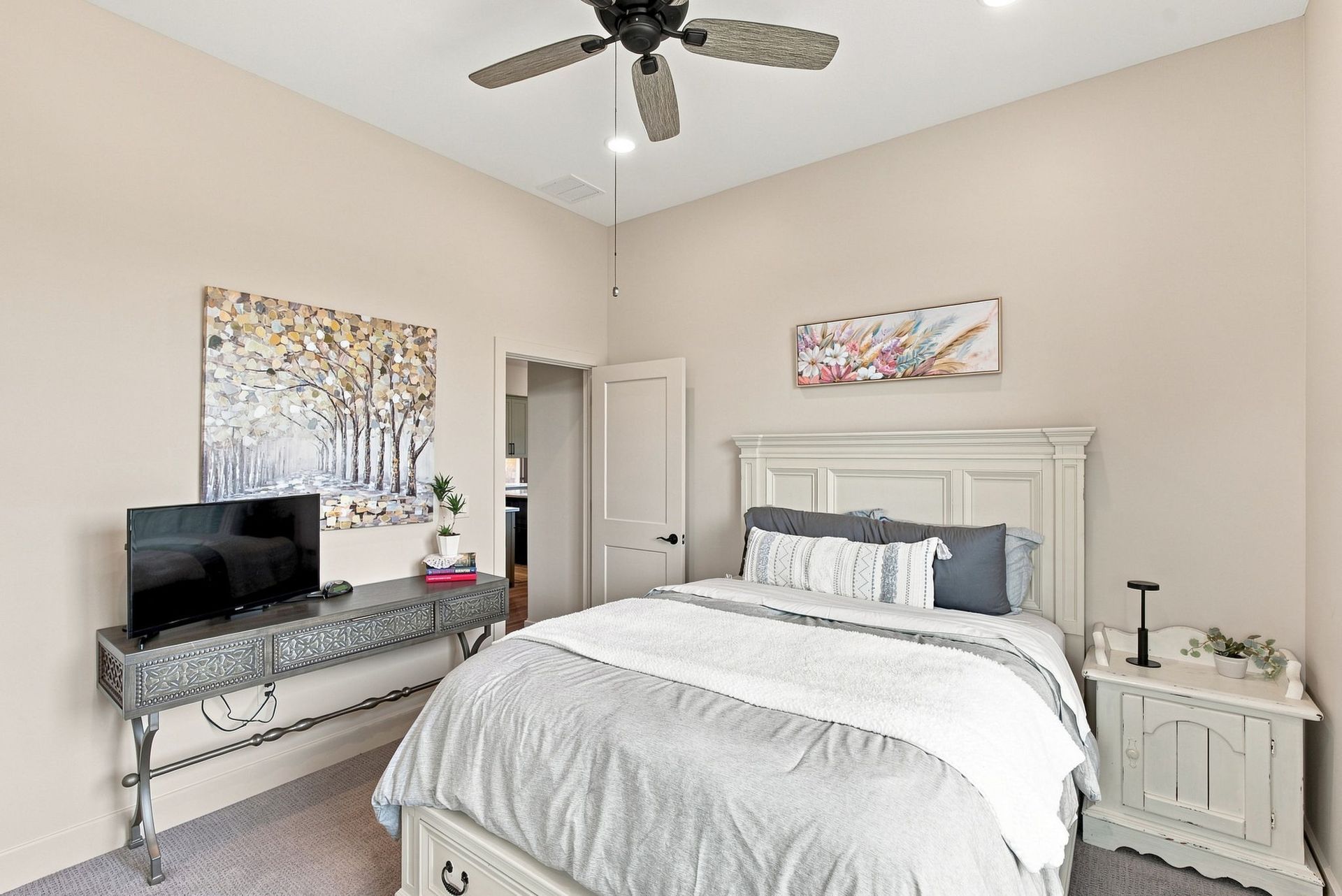 Bright bedroom with a bed, nightstands, dresser, TV, and ceiling fan