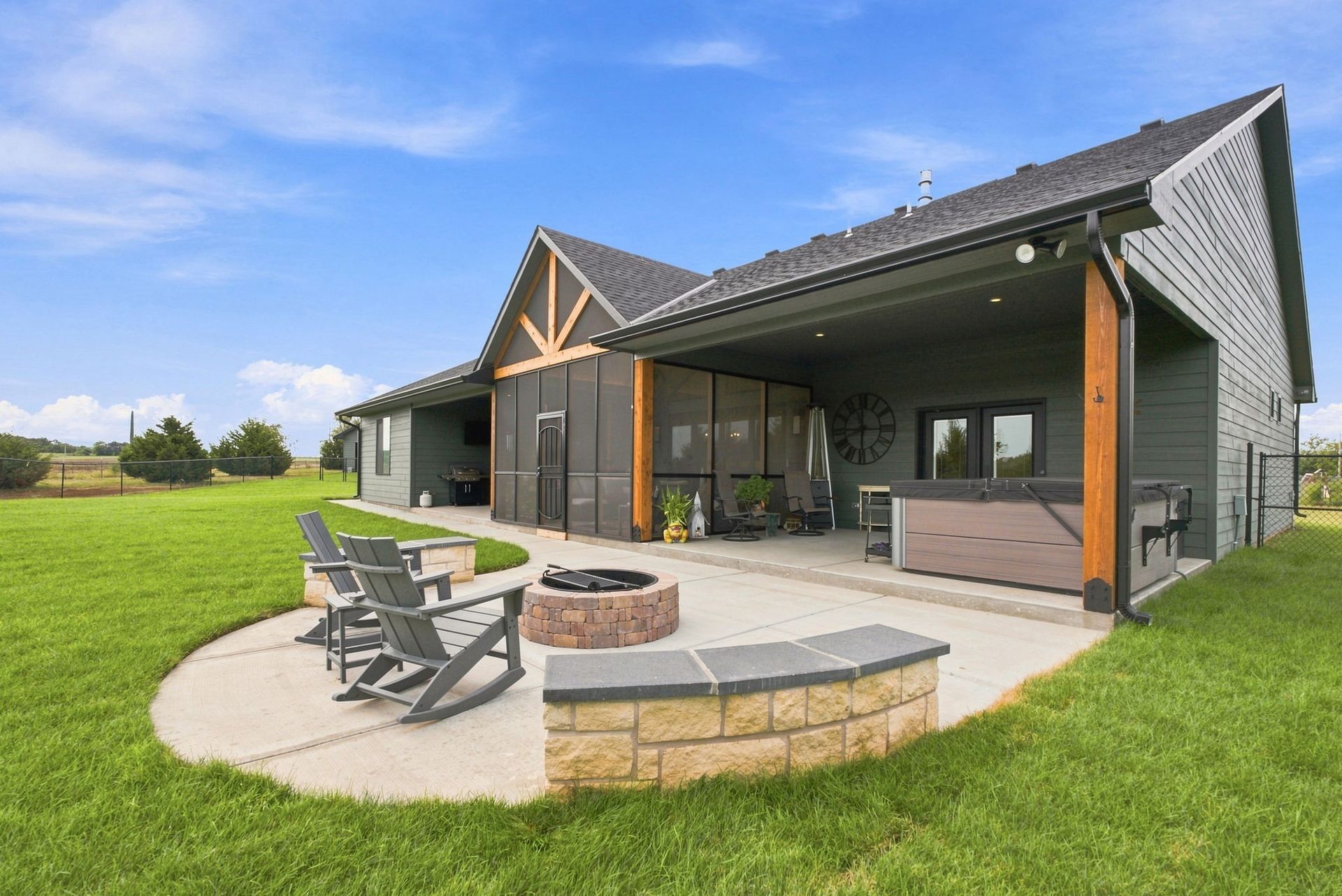 Modern house with covered patio, fire pit, and lounge chairs on a grassy lawn