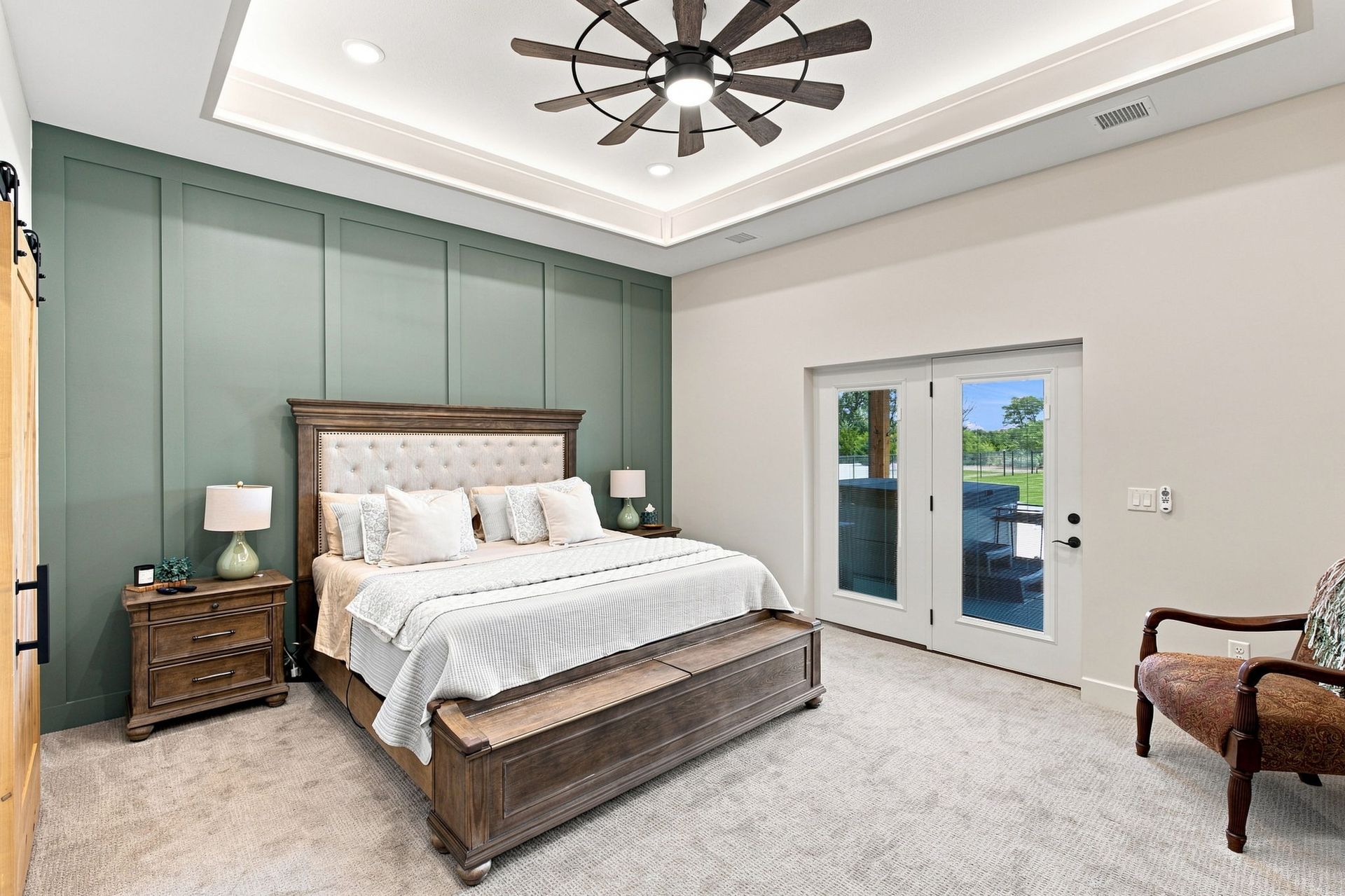 Bright bedroom with a wooden bed, nightstands, ceiling fan, and French doors to a balcony.