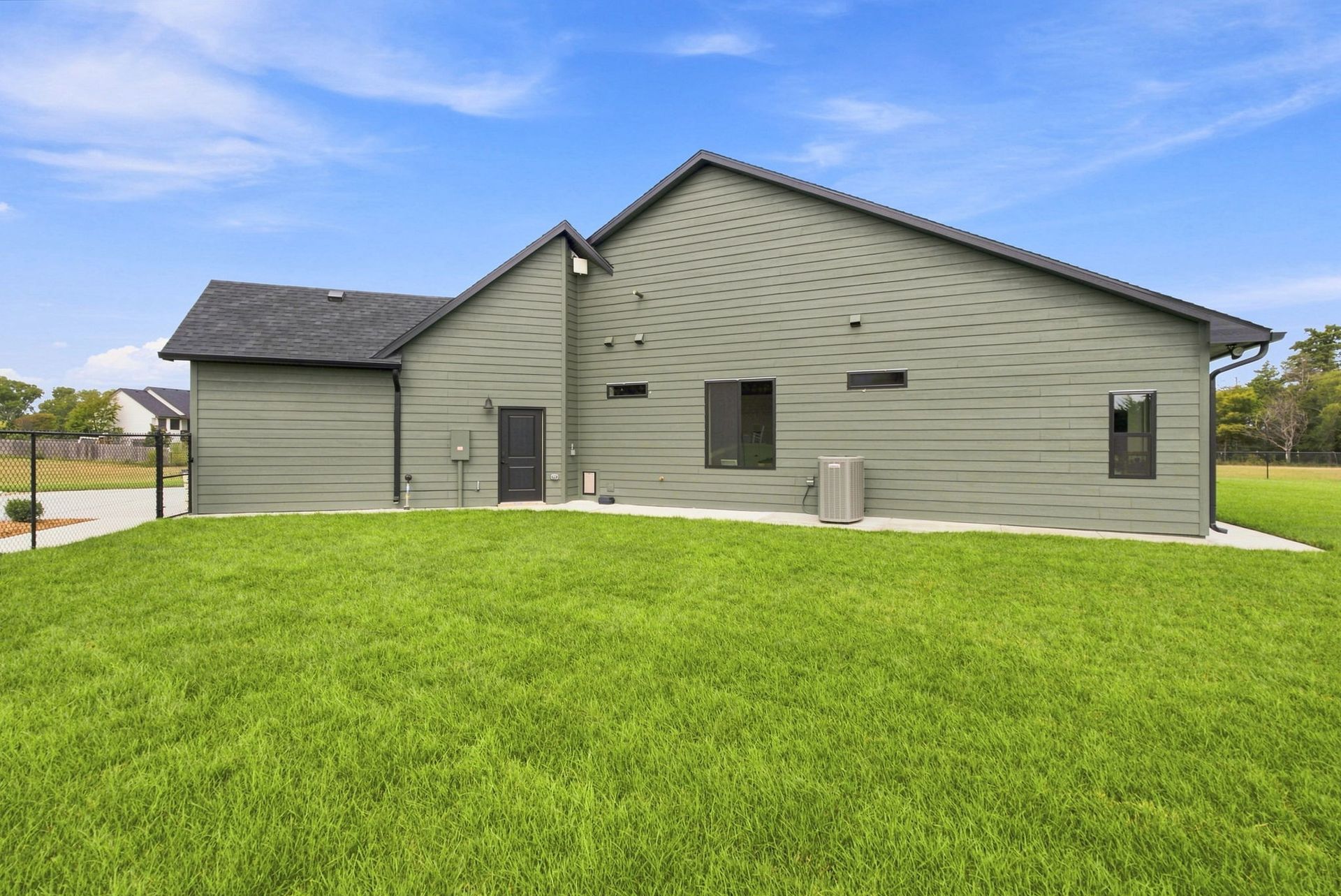 Gray house with a green lawn under a blue sky
