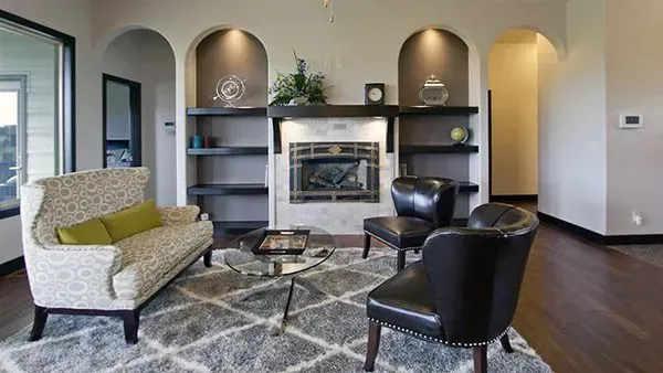 Modern living room with fireplace, arched alcoves, patterned rug, and black and cream chairs