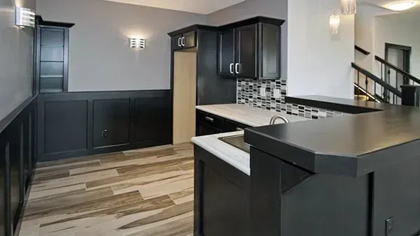 Modern kitchen with dark cabinets, light countertops, and wood-look flooring