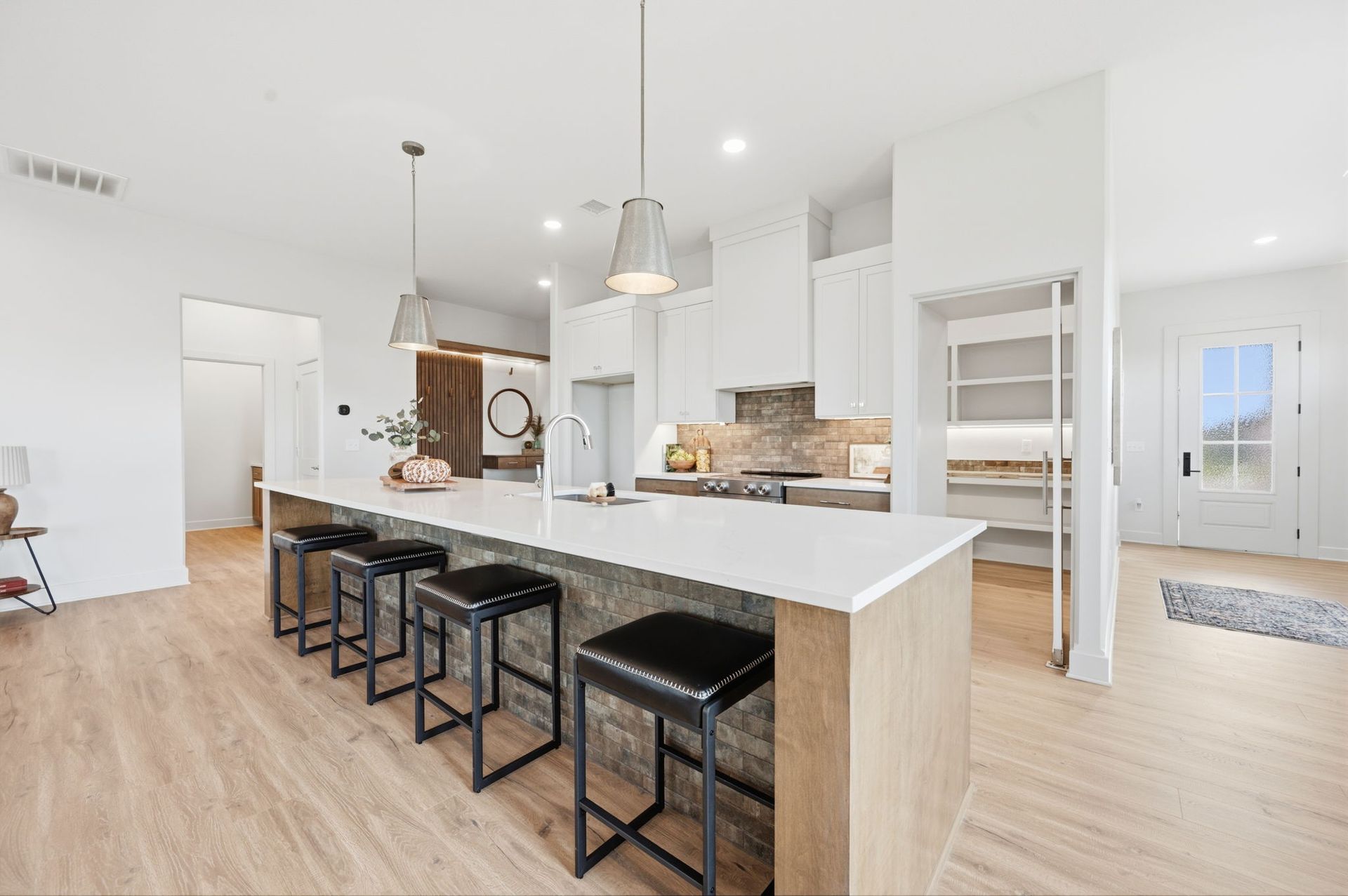 Bright modern kitchen with white cabinets, island, and black stools in an open living space