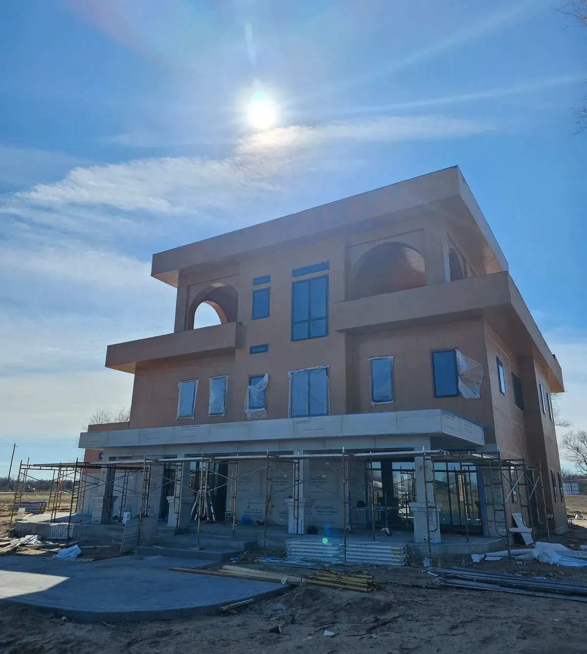 Three-story brick building under construction on a sunny day, with scaffolding around the ground floor.