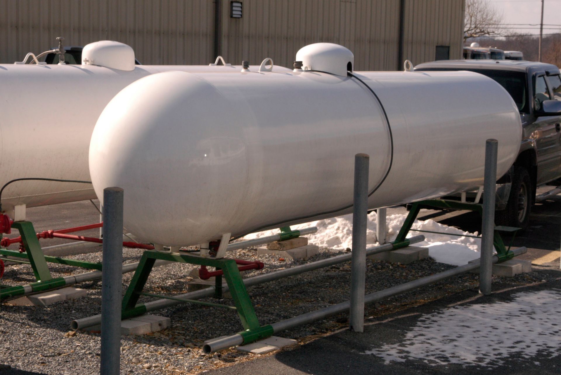 White propane tanks on green metal stands, outdoors.