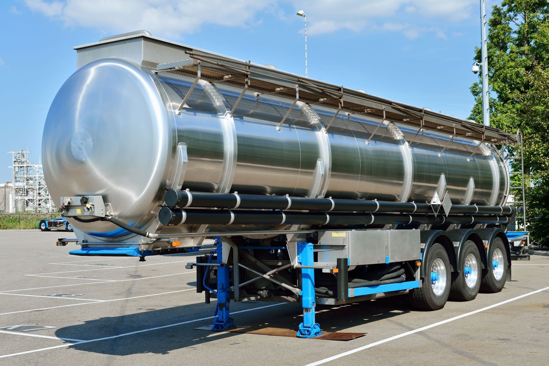 Stainless steel tanker trailer parked on asphalt.